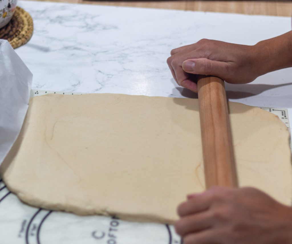 hand holding a rolling pin rolling the dough
