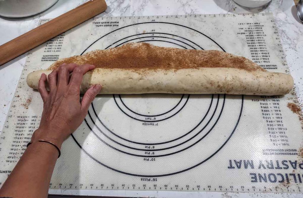hand rolling a cinnamon roll log