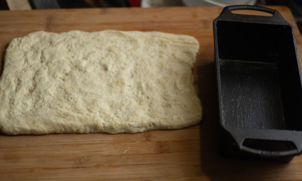 honey oat dough in rectangular shape in cast iron loaf pan