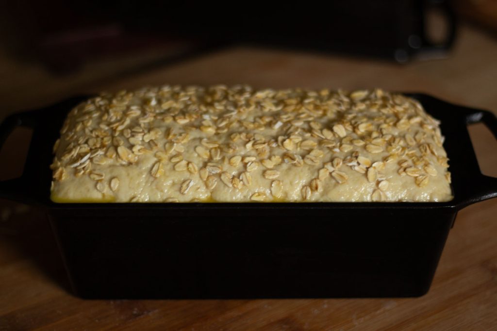 proofed honey oats dough inside loaf cast iron pan