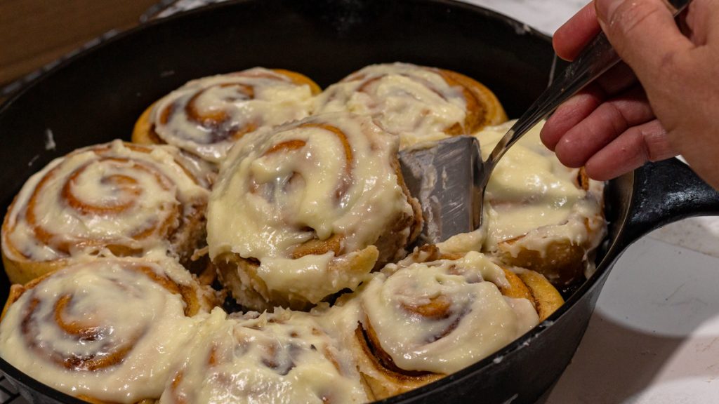 hand holding a pie knife with s sourdough brioche cinnamon rolls