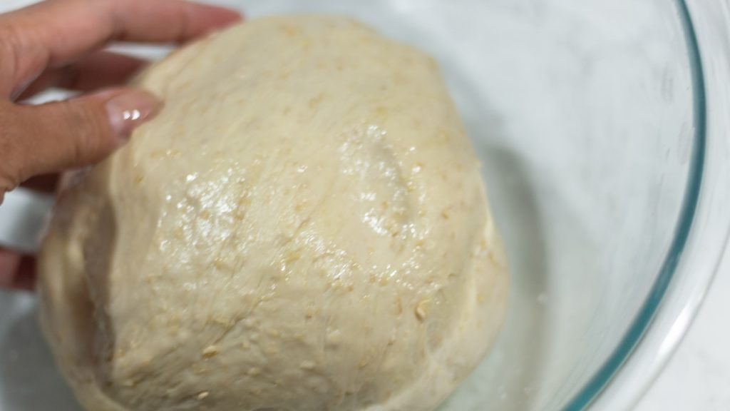 wet honey oat rolled dough inside oiled bowl