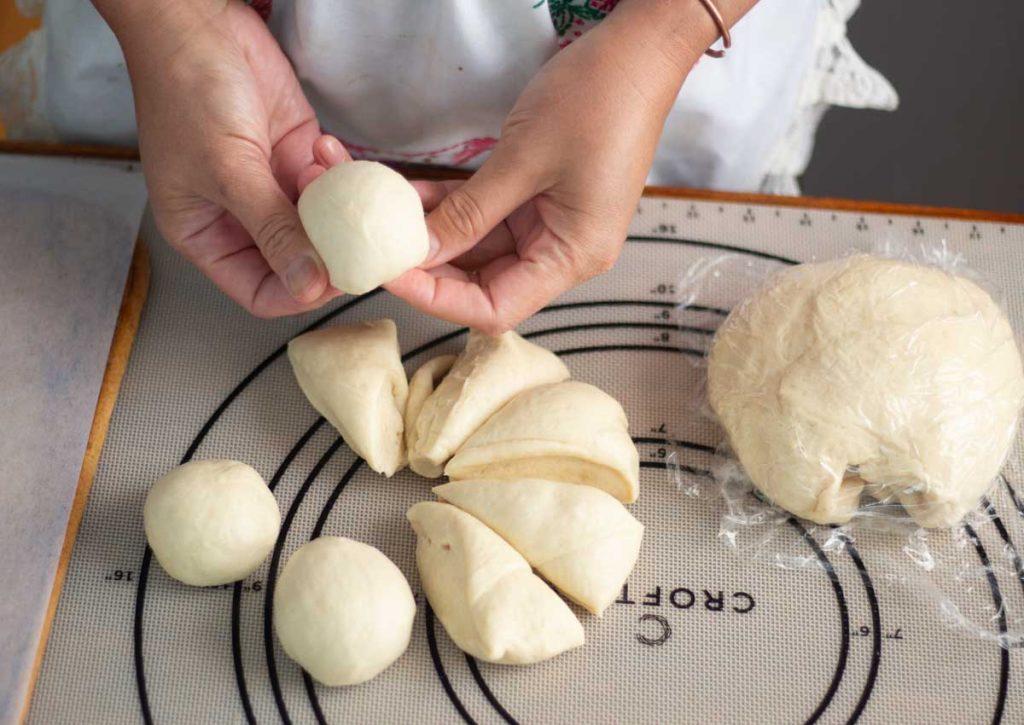 hand holding rounded dough balls over sliced sourdough