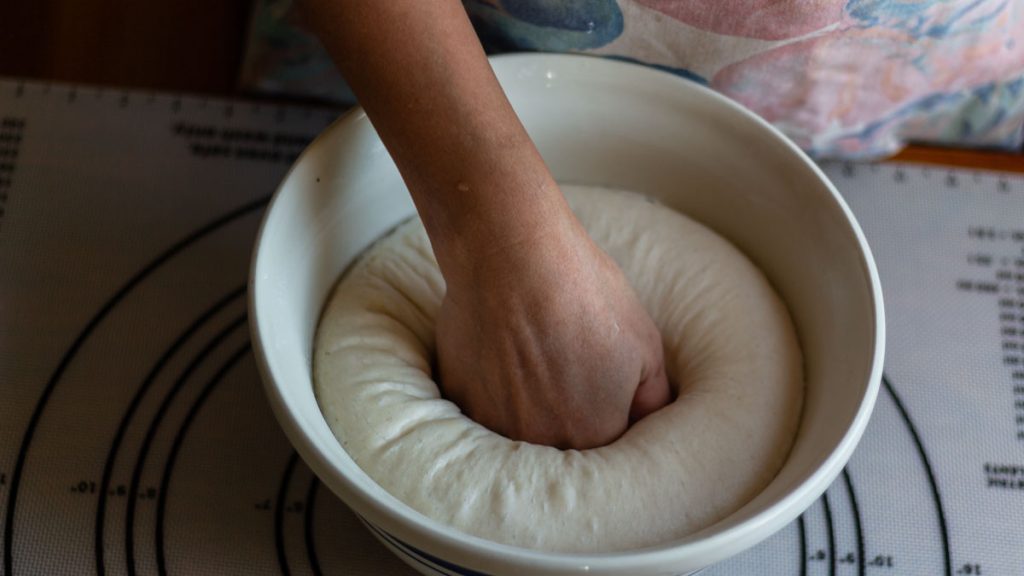 hand on wet sourdough inside mixing bowl
