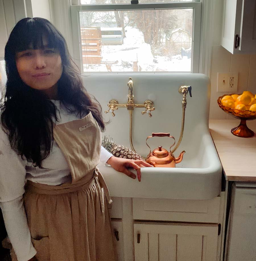 woman standing in front of a vintage hutch